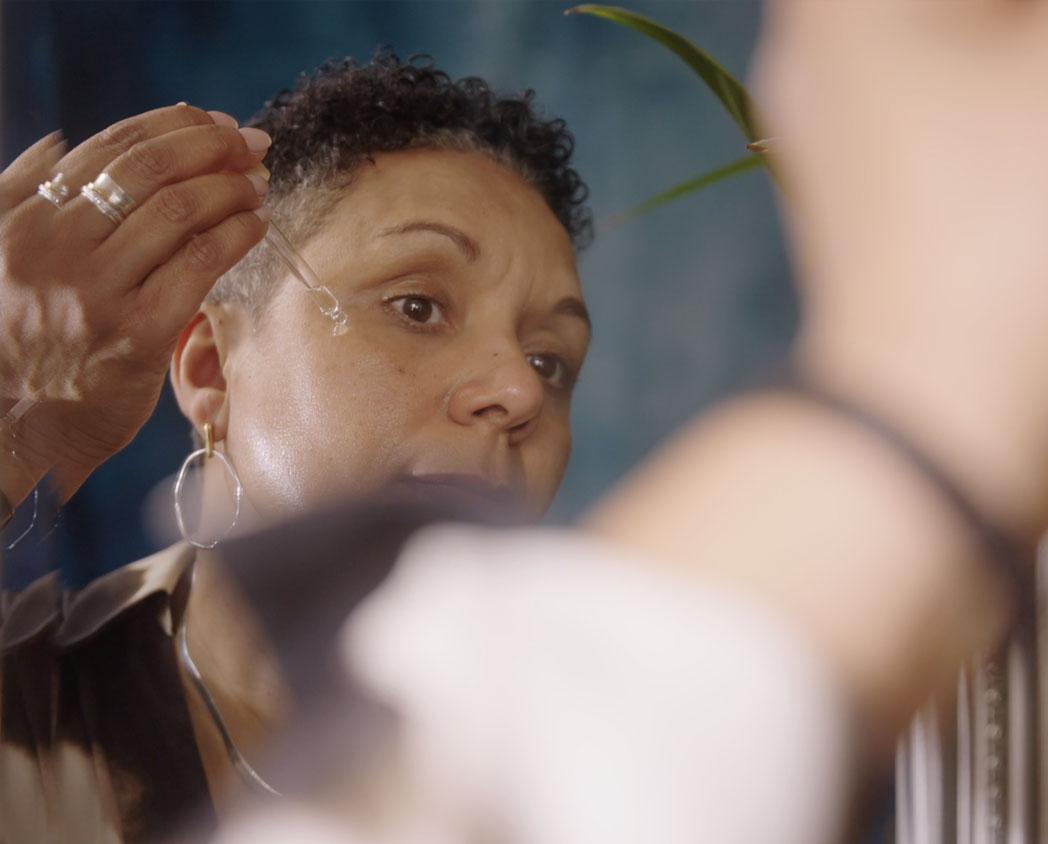 Woman applying face serum in the mirror